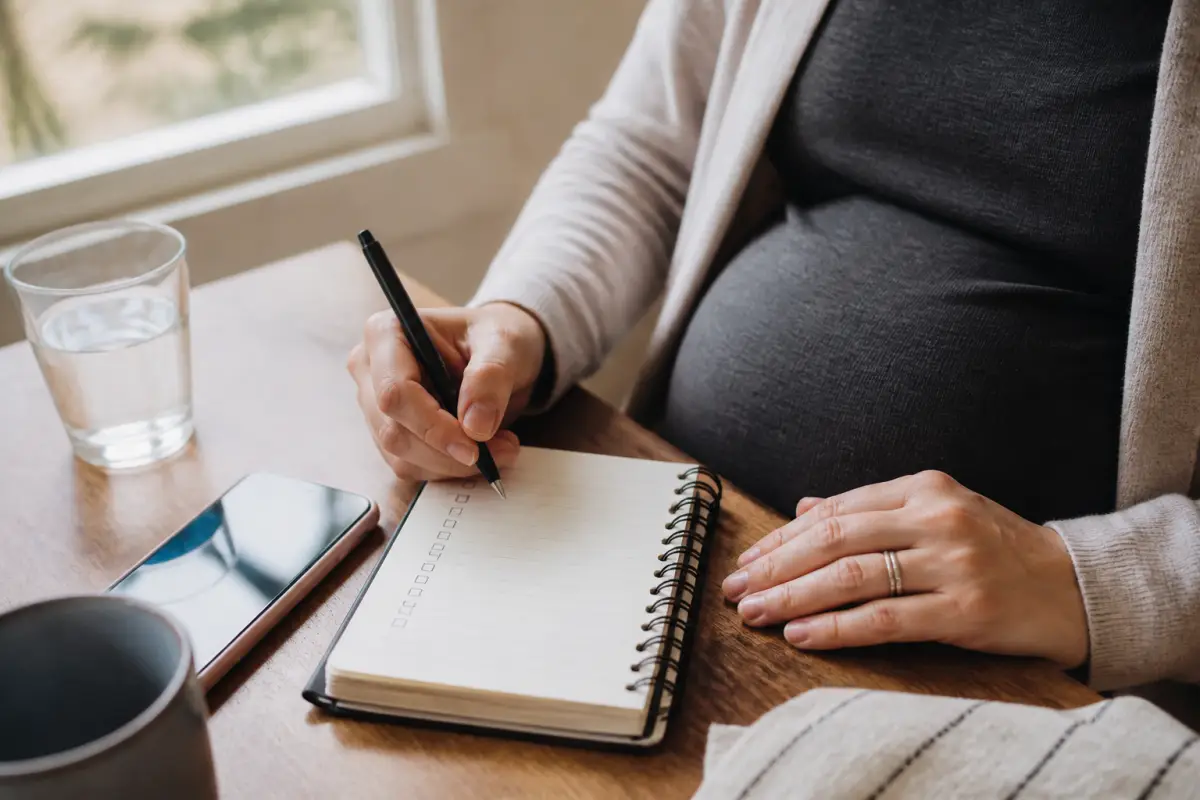 Pregnant client writing appointment questions in a notebook