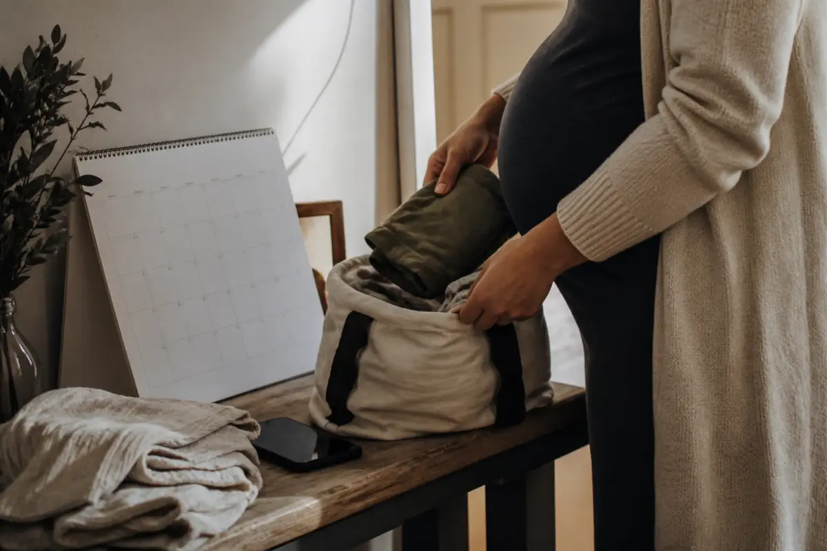 Pregnant client packing loose clothing beside a calendar before an appointment